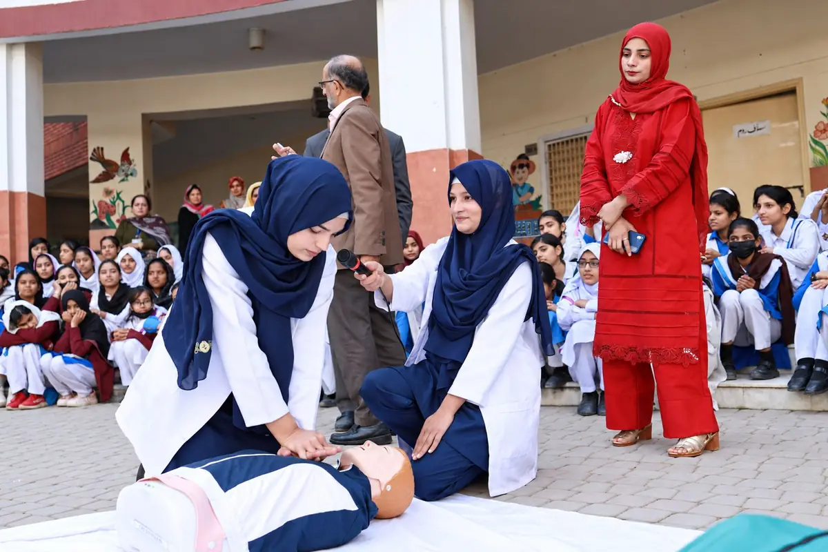 An instructor demonstrating first aid on a training manikin with a colleague supporting the session